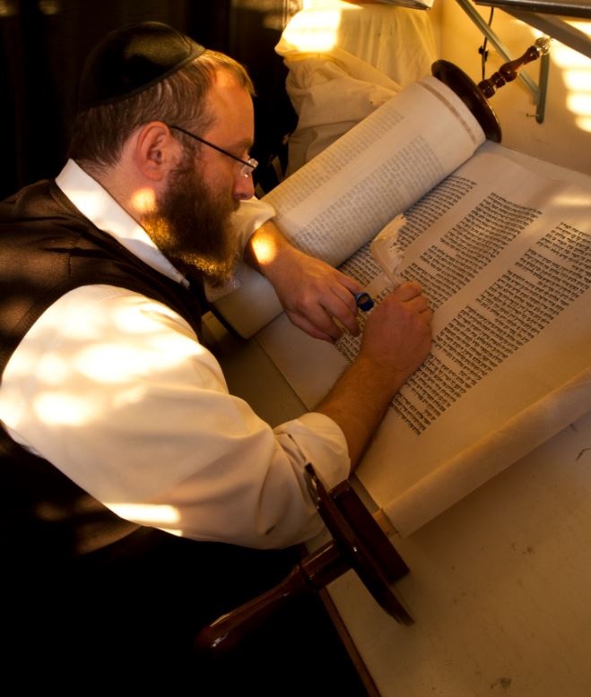 Rabbi Eli Gutnick carefully working on a Torah scroll